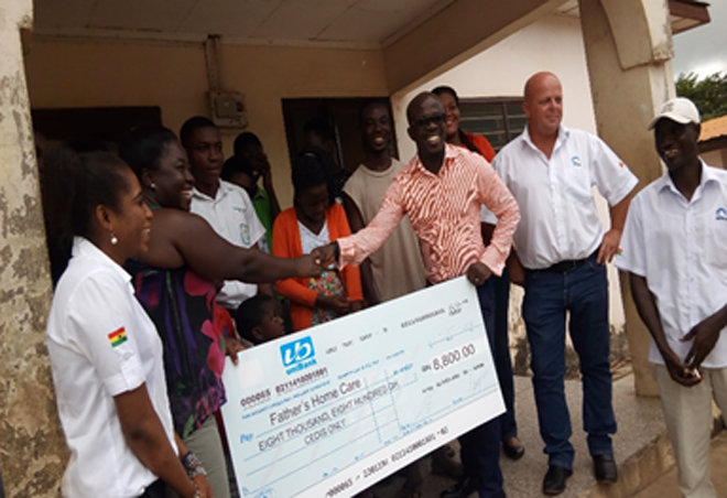Mr Micheal Preprah (3rd right), Finance Manager of TETRA B.V, presenting the cheque to Madam Yamoah while staff of the company look on Mr Micheal Preprah (3rd right), Finance Manager of TETRA B.V, presenting the cheque to Madam Yamoah while staff of the company look on