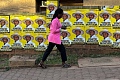 A woman uses a mobile phone as she walks past campaign posters of Yoweri Museveni, Uganda's President and presidential candidate of the ruling National Resistance Movement (NRM), ahead of the general election in Kampala, Uganda, January 14, 2026. REUTERS/Thomas Mukoya