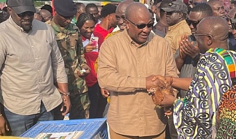 President John Dramani Mahama handing over a fowl to Akyamfour Asafo Boakye Agyemang(in Kente), the Asafohene, to officially launch the 