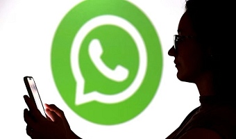 A teenager poses for a photo while holding a smartphone in front of a Whatsapp logo in this illustration taken September 11, 2025. REUTERS/Dado Ruvic/Illustration/File Photo
