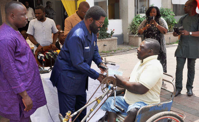 The CEO of the AMA, Mr Alfred Okoe Vanderpuije (middle), presenting a cheque to one of the beneficiaries at a ceremony in Accra GH¢108,000 disbursed to PWDs in Accra