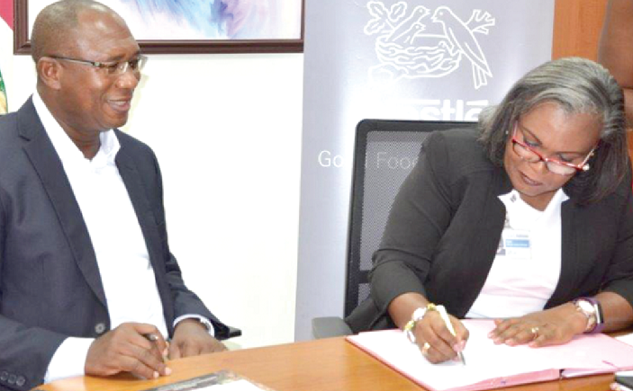 Mrs Freda Duplan (right) signing the MoU. With her is Dr Emmanuel Dormon Two organisations partner to train farmers on quality grain production