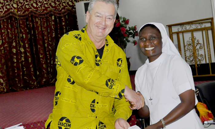 Mr Morten Gade (middle) handing over a cement allocation chit to a representative of a beneficiary institution