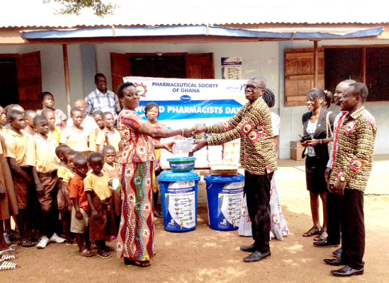 Mr Divine Azameti, Regional Pharmacist, presenting the items to the Headmistress of the Airfield Complex