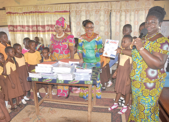 Mrs Jane Marshall Amissah (right), Head of Marketing, Multi Credit Savings &amp; Loans Limited (MCSL), making the presentation on behalf of Mr Kwabena Kesse to Madam Theresa Baako, the Headmistress of the Akosa M/A Primary School, while some teachers and pupils of the school look on