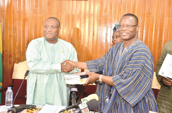 The Minister of Health, Mr Alex Segbefia, (left) receiving the report from Dr Chris Atim