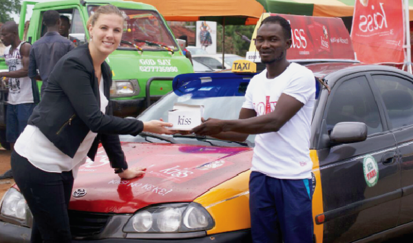 Ms Kelly De-Vries Adosu, the Marketing Manager of DKT Ghana, presenting a packet of Kiss condoms to one of the drivers NGO initiates public education on sexual, reproductive health