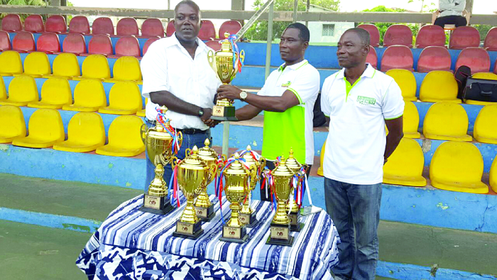 Dr Antwi Tetteh(middle) presenting one of the trophies to Mr Isaac Duah while the tournament referee, Yakubu Lea, looks on