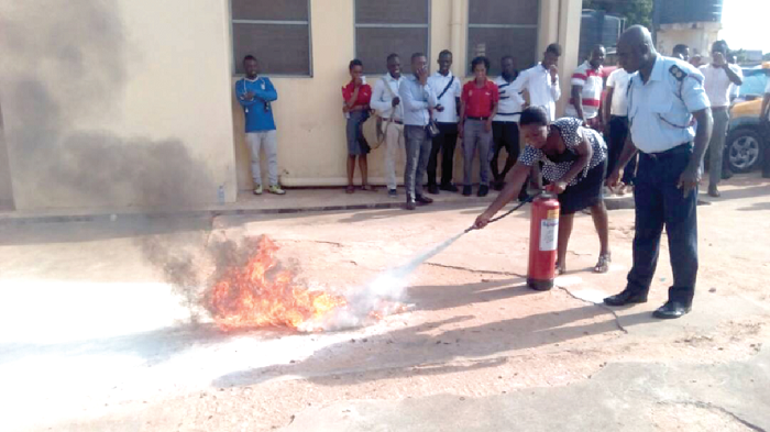A fire officer (right) supervising a filling station attendant on how to use the fire extinquisher A fire officer (right) supervising a filling station attendant on how to use the fire extinquisher