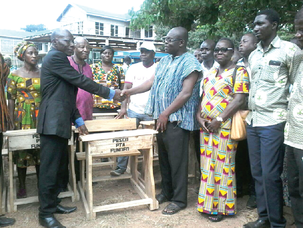 Mr Christian Kofi Ani-Frimpong (right) presenting the desks to the Headmaster, Mr Jonathan Agbley