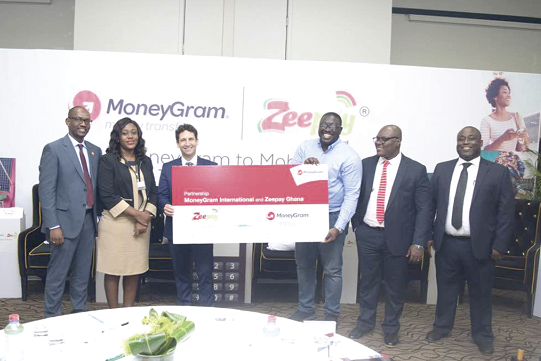 • Mr John Gely (3rd left), Head of MoneyGram, Africa exchanging the symbolic partnership card with Mr Andrew Takyi-Appiah, MD of Zeepay Ghana Limited. Looking on are officials of MoneyGram and Zeepay