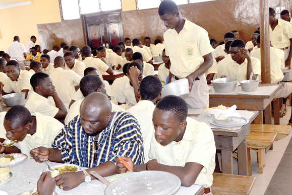•  Alhaji Abdul-Wahab, Chief Executive Officer of the NAFCO (in smock), at lunch with students of Accra Academy during his visit to the school.