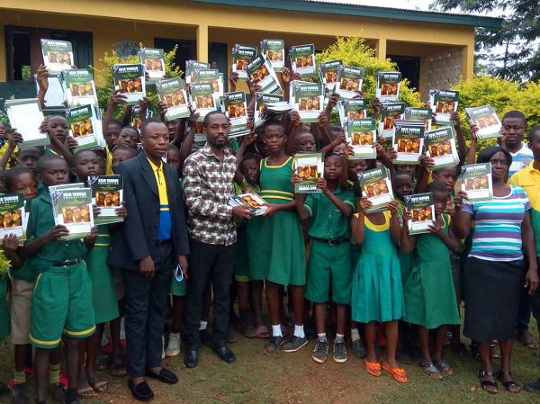 Mr Patrick Kojo Yamoah presenting the exercise books to the pupils Mr Patrick Kojo Yamoah presenting the exercise books to the pupils