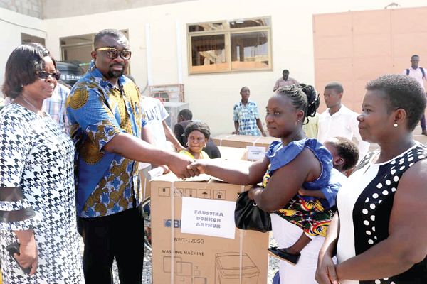  Patrick Kwasi Brako Kumor (2nd left), Municipal Chief Executive of Weija-Gbawe, presenting a deep freezer to  Madam Faustina Donkor Arthur (right), one of the beneficiaries. Looking on is Ms Mercy Quansah, the Municipal Coordinating Director 