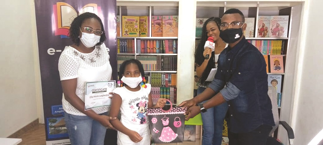 Ella-Maria receiving her prize from Mr Cephas Larbi, the Director of e-Ananse Libraries, while her mother, Mrs Cheir Legbedze (Left), looks on. e-Ananse awards winner of colouring contest
