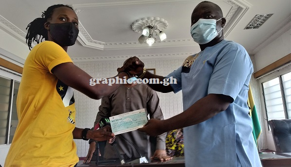 The Special Assistant of the Minister of Youth and Sports, Mr Kofi Asare Brako handing over the cheque to Black Queens goalie Patricia Mantey