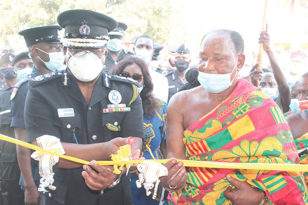 Mr Oppong-Boanuh , the IGP, being assisted by Nana Ansah Adu Baah (right) to cut the tape to inaugurate the new police station Yamfo gets district police station