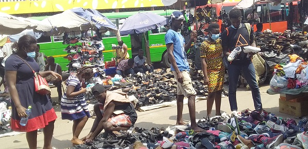A school girl (arrowed) trying a shoe on while other students look around to see if they will get something of their choice. Parents shop for kids as schools reopen