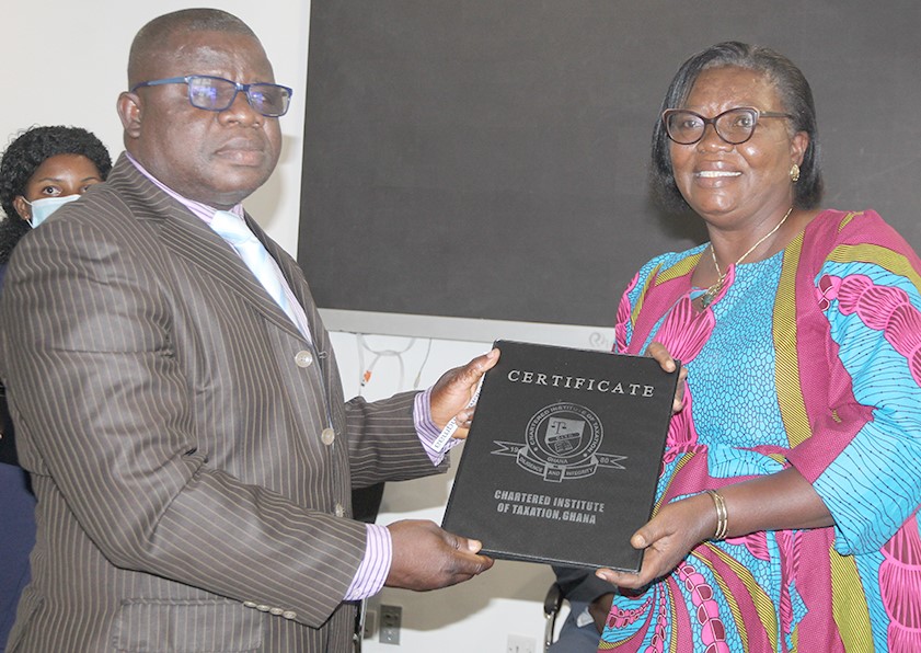 Ms Esi Duma Sam (right), a member of the outgoing Council of the CITG, presenting a certificate to Mr Albert Kungmaa Ziem (left), Management Accountant, Graphic Communications Group Ltd, after he was inducted into the institute in Accra.