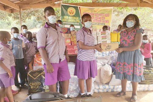 Joana Kensema Odei-Larbi (right), the Taifa Area Manager of Asa Savings and Loans Limited, handing over the items to one of the children in the Christ Faith Foster Home while other children looked on Joana Kensema Odei-Larbi (right), the Taifa Area Manager of Asa Savings and Loans Limited, handing over the items to one of the children in the Christ Faith Foster Home while other children looked on