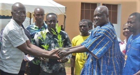 Evans Kusi Boadum (2nd from right), the Sunyani West Municipal Chief Executive, presenting a seedling to one of the beneficiary farmers