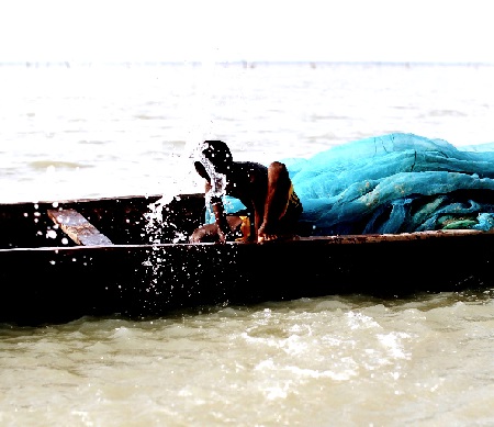 A child drawing water from a canoe on the Volta lake 