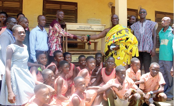 Nana Kwesi Addo II (right), Gyasehene of Pankese presenting the desks to Mr Peter Kwaku Ofori (left), head teacher of the Pankese DA Junior High School, while other staff and pupils of the school look on Nana Kwesi Addo II (right), Gyasehene of Pankese presenting the desks to Mr Peter Kwaku Ofori (left), head teacher of the Pankese DA Junior High School, while other staff and pupils of the school look on