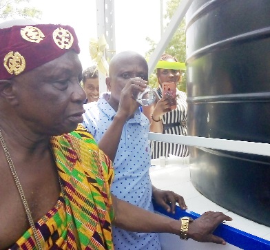 Joe Sam, Upper Manya Krobo District Chief Executive, drinking water from the new facility. With him is Nene Tettey-Ku Gbadadji, Chief of Asesewa