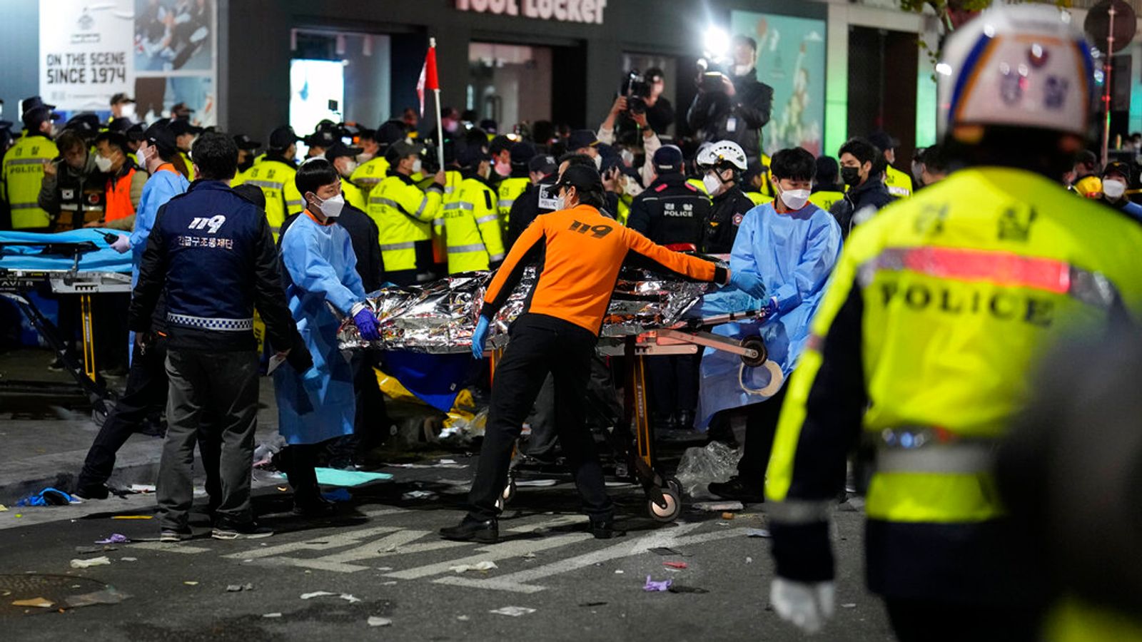 Rescue workers carry a victim on the street near the scene in Seoul South Korea declares national period of mourning after Halloween crowd crush kills 153