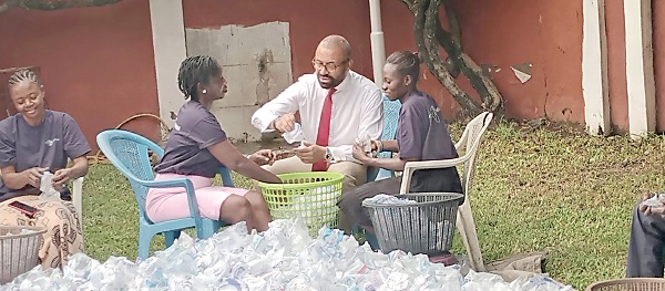 James Cleverly (middle), UK Secretary of State for Foreign, Commonwealth and Development Affairs, joins two staff members of Trashy Bags Africa, to work on some empty sachets during his visit to the company James Cleverly (middle), UK Secretary of State for Foreign, Commonwealth and Development Affairs, joins two staff members of Trashy Bags Africa, to work on some empty sachets during his visit to the company