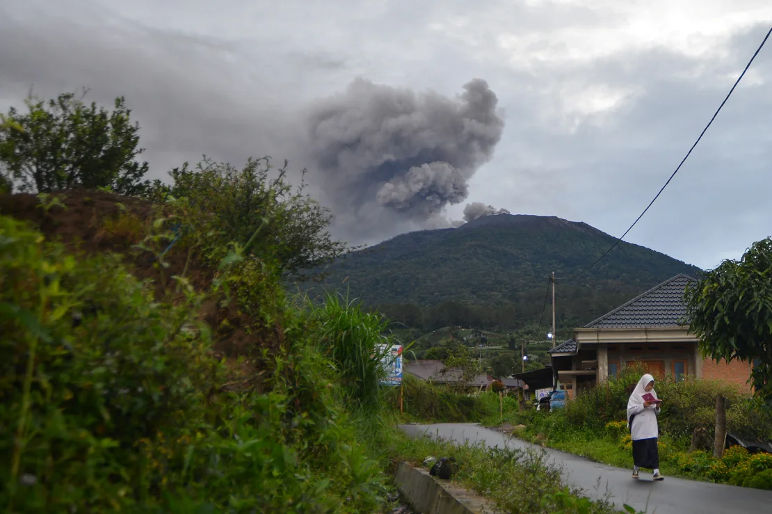 A student walks as Mount Marapi volcano spews volcanic ash as seen from Nagari Batu Palano in Agam, West Sumatra province, Indonesia, December 4, 2023. Indonesian volcano eruption