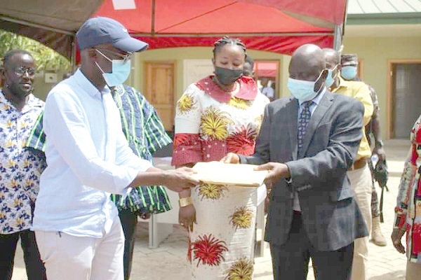 Stephen Yakubu (right), Upper East Regional Minister, handing over the project documents to Jawad Abdul-Rakeeb (left), the contractor, while Rita Atanga, DCE for Bongo District, looks on during the sod-cutting ceremony