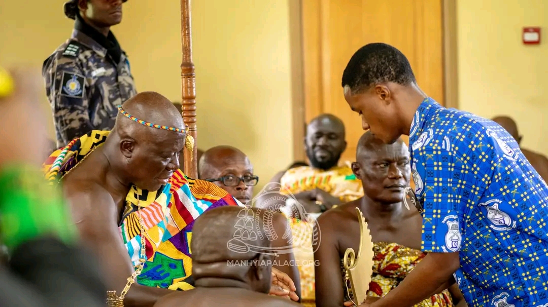 Otumfuo Osei Tutu II (L) receiving the maiden STEMNNOVATION trophy from a contestant (R) from Kumasi Academy at Manhyia Palace Kumaca presents STEMNNOVATION trophy to Otumfuo at Manhyia Palace