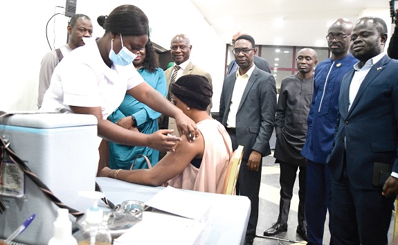A woman receiving a COVID-19 jab from a health official at the launch. Looking on is Dr Patrick Kuma-Aboagye (left behind) and some officials. Picture: EMMANUEL QUAYE A woman receiving a COVID-19 jab from a health official at the launch. Looking on is Dr Patrick Kuma-Aboagye (left behind) and some officials. Picture: EMMANUEL QUAYE