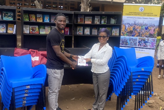 Hans Nunoo Sarpei (left) presenting a copy of the books to Madam Vincentia Korkuvi, 28th February Road & Private Odartey Memorial Basic School