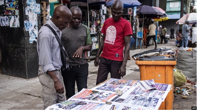 Men look at newspaper headlines in Monrovia, Liberia, on Oct. 11, 2023, after Liberians voted in their general elections. Liberia election commission finalising results of Tuesday's polls
