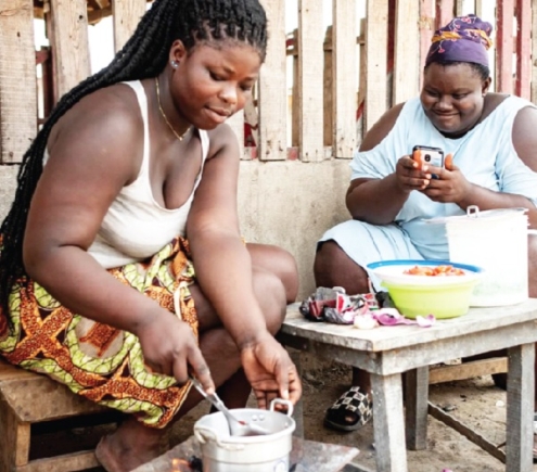 Two women cooking and engaging online with a mobile phone 