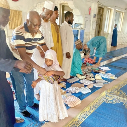 lbrahim Muhammed (2nd from left) presenting a set of dress to one of the orphans. Standing on his left in white attire is Nuhu Muhammed Abdalla, the Municipal Chief Imam lbrahim Muhammed (2nd from left) presenting a set of dress to one of the orphans. Standing on his left in white attire is Nuhu Muhammed Abdalla, the Municipal Chief Imam