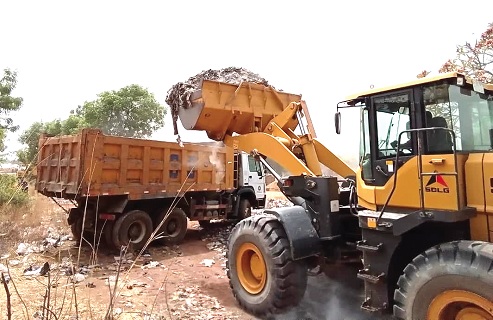 A pay loader evacuating refuse at a dump site into a truck A pay loader evacuating refuse at a dump site into a truck