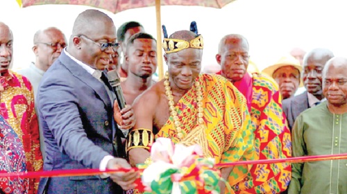Torgbui Abordor VIII, Divisional Chief of the Anyigbe Clan, Agave, being assisted by Dr Bryan Acheampong (left), Minister of Food and Agriculture, to cut the ribbon to officially hand over the facilities