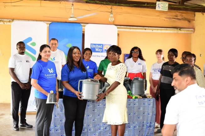 Asiedua Addae Head (2nd left), Corporate Affairs, Brand and Marketing, Standard Chartered Bank Ghana PLC, presenting some gardening tools to a representative of Kanda Cluster of Schools Stanchart promotes sustainability in public schools