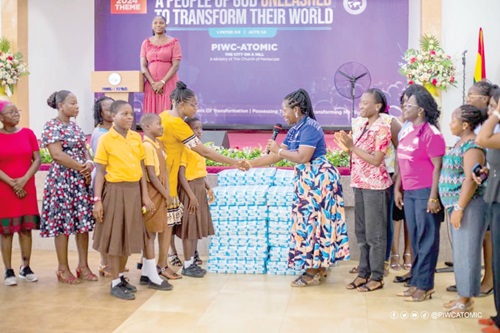 Gifty Agyemang, the women's leader for PIWC-ATOMIC, presenting the sanitary pads on behalf of Precious Pearls to a representative from the Atomic Cluster of Schools