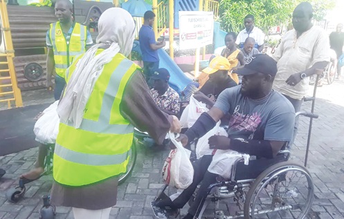 A volunteer at TUDEC presenting a parcel to a PWD