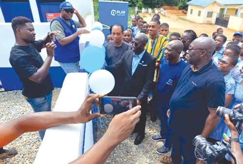 Eric Ayaba (2nd from left) being assisted by Frank Boamah (left), Head of Programmes and Influencing, to cut the ribbons during the hand over ceremony. INSET: The facility Eric Ayaba (2nd from left) being assisted by Frank Boamah (left), Head of Programmes and Influencing, to cut the ribbons during the hand over ceremony. INSET: The facility