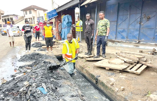 Adamu Musa Kalamu (with a shovel), MCE for Ablekuma North,  clearing silt from a gutter during the exercise.