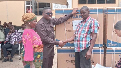 Emmanuel Adotey Allotey, the Ga Central Municipal Chief Executive, presenting an item to a visually impaired beneficiary