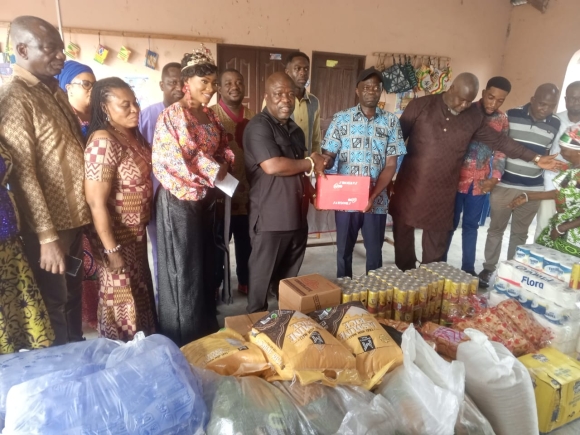 James Gunu, Volta Regional Minister presenting the items to Nelson Atito, caretaker of the Ho Cured Lepers Village, while Queen Etornam and some District Chief Executives look on