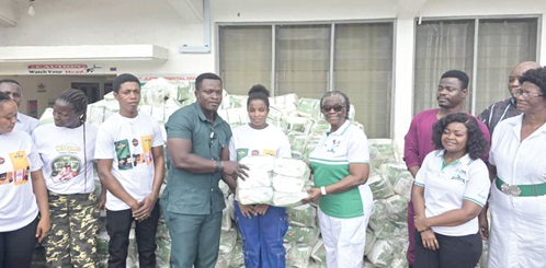 Dr Collins Amo (middle) presenting some of the diapers to one of the beneficiaries