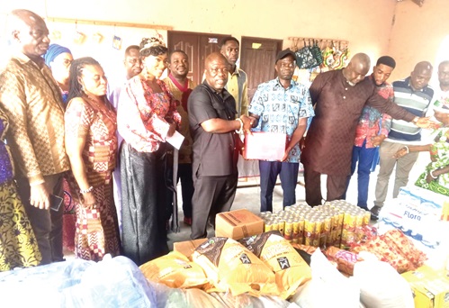James Gunu (4th from left), Volta Regional Minister, presenting the items to Nelson Atito, the Caretaker of the Ho Cured Lepers Village, while Queen Etornam (3rd from left) and some district chief executives look on