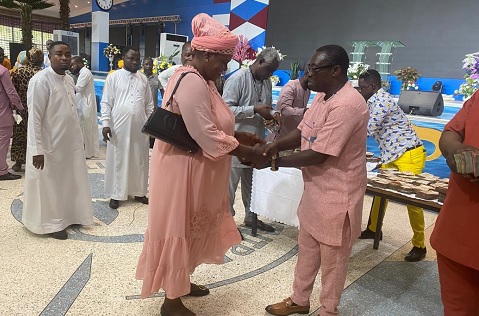 A leading member of the church presenting the money to one of the beneficiary traders
